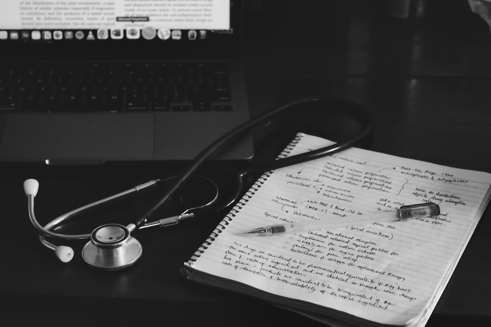 Stethoscope and handwritten intake notes beside a laptop